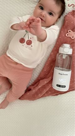 Babycozidoo bottle warmer next to a smiling baby on a playmat