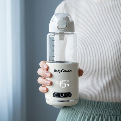 Australian mum in cream knit jumper holding the Babycozidoo Portable Bottle Warmer at 45 degrees Celsius — easy one-hand grip on the go