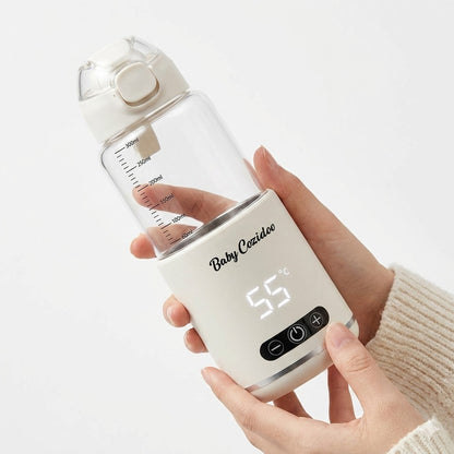 Close-up of two hands holding the Babycozidoo Portable Bottle Warmer Pro displaying 55 degrees Celsius — real-life size and one-hand portability